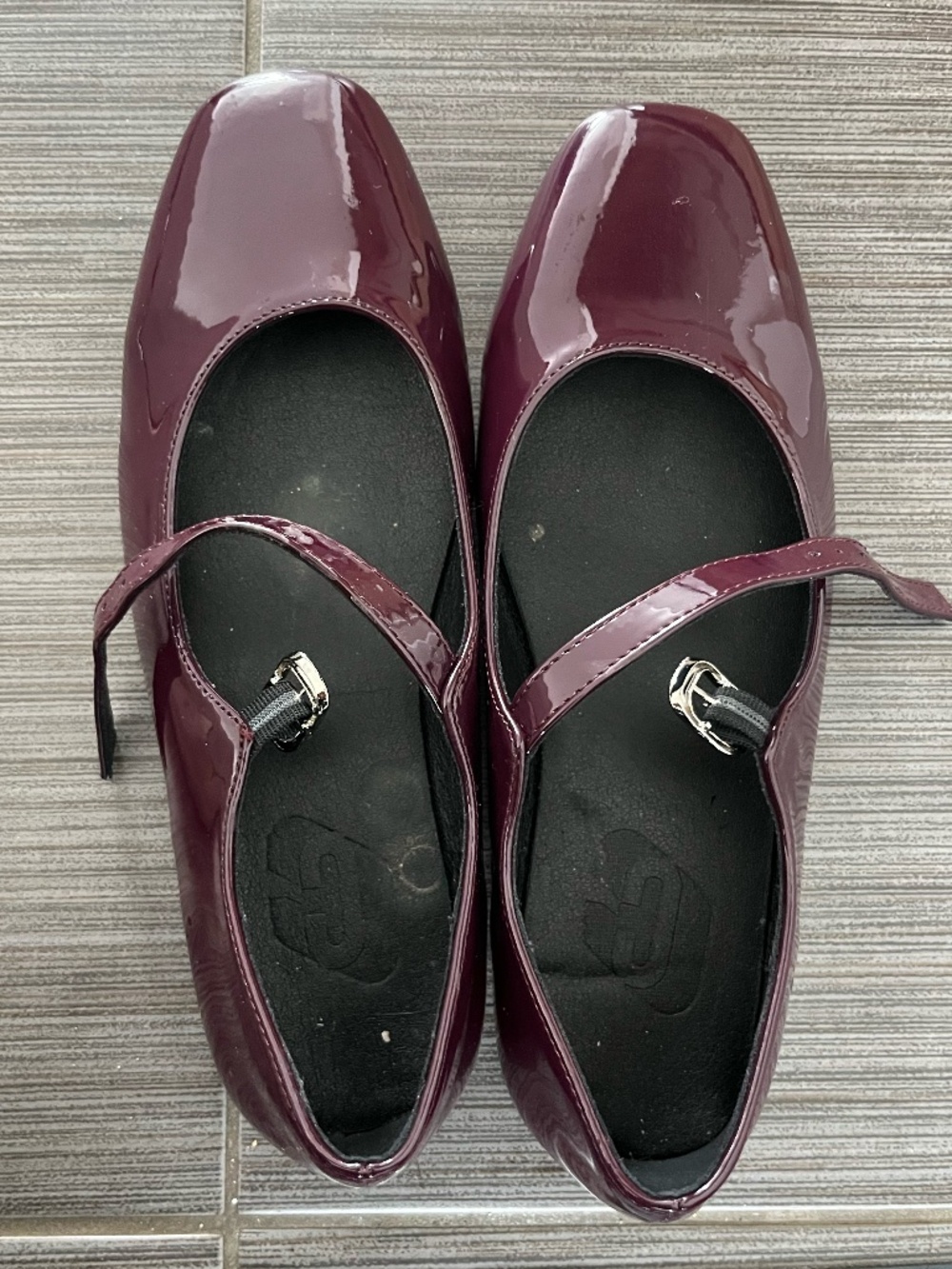 Burgundy patent leather Mary Janes. Features a classic square toe and adjustable